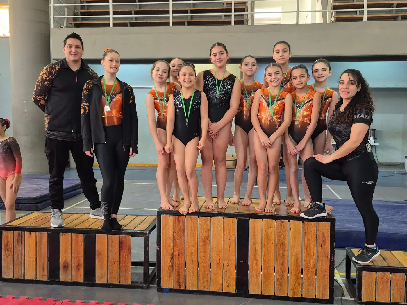 Equipo de gimnastas del Olímpico arriba del podio con sus medallas